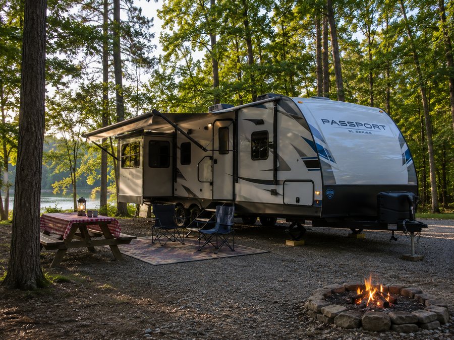 Travel trailer at a wooded lakeside campsite